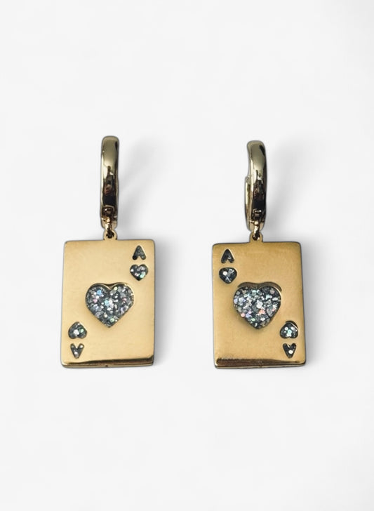 Gros plan net sur les deux boucles Heartbreaker : on voit parfaitement la forme de la carte As et l’éclat du cœur en émail pailleté. Un visuel parfait pour montrer le rendu général porté ou en présentation.