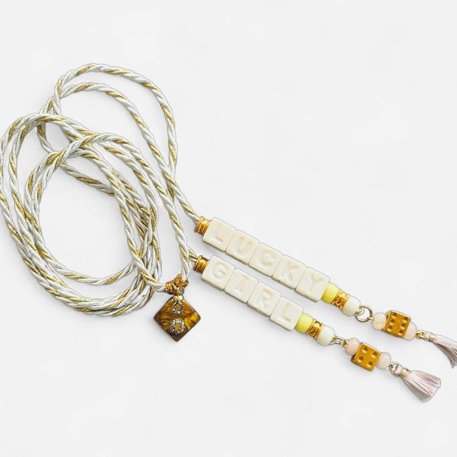 Collier Casino Club blanc et doré avec perles lettres “LUCKY GIRL”, dés dorés, pompons pastel et médaillon vintage.
