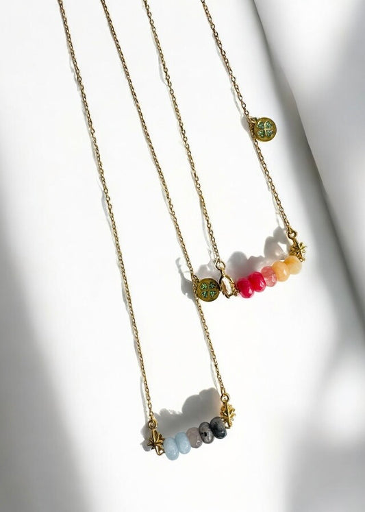 Colliers Divaine personnalisables avec 5 pierres de naissance, modèles posés sur fond blanc en lumière douce.