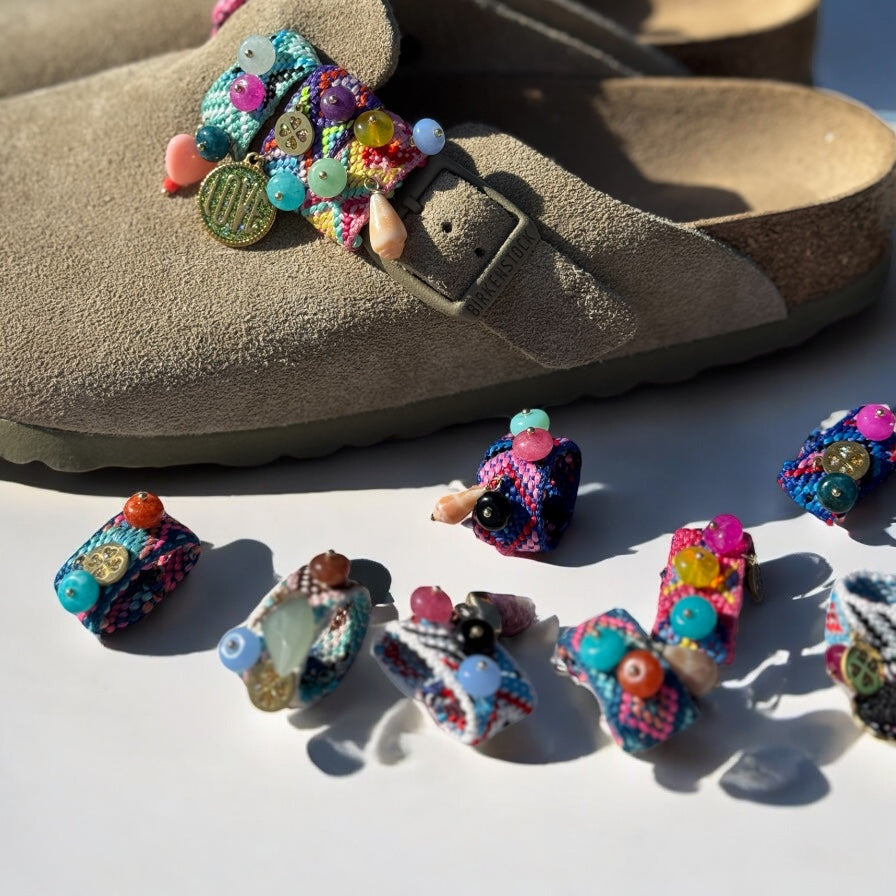 Sandales Birkenstock customisées avec plusieurs paires de Sandalinettes colorées tressées et perlées, présentées en extérieur.